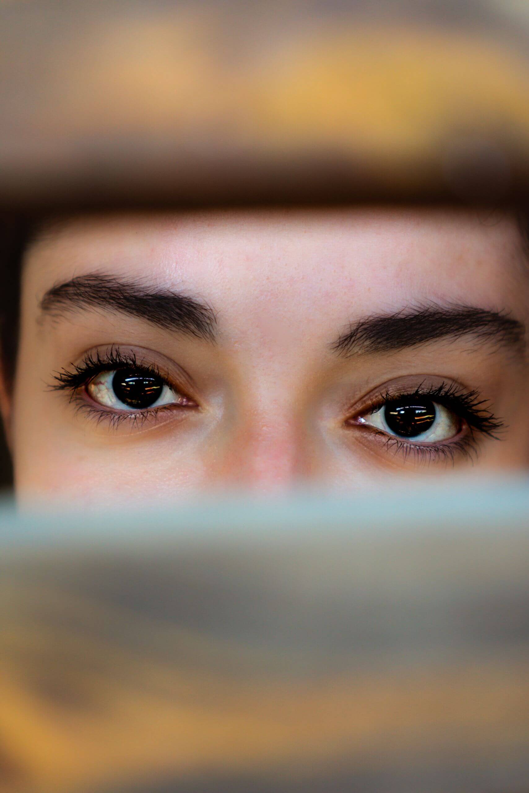 A mysterious and artistic close-up of a woman's eyes peeking through slats, capturing emotion.
